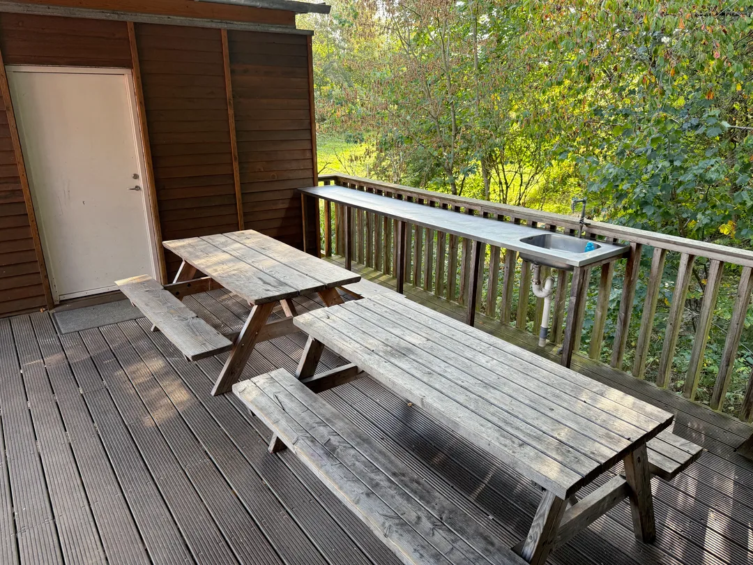 Overdækket terrasse med bænke og udendørs vask
